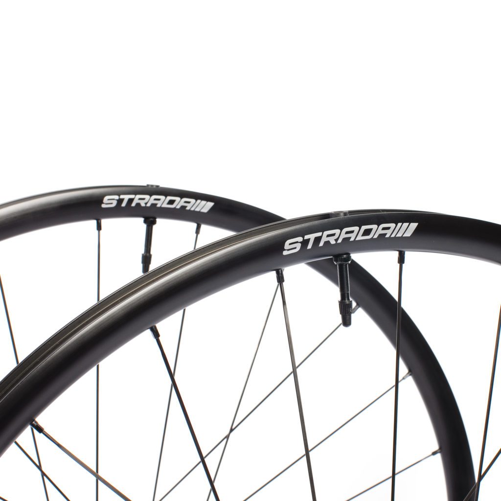 A close photo of the Strada All Season Disc road bicycle wheel set with Black rims and spokes and a white Strada logo