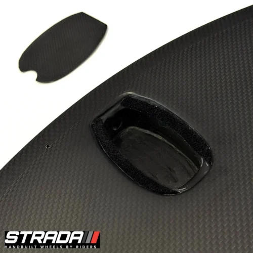 A picture showing a a close up of the valve access of carbon Strada Ultra TT Disc disc Brake rear wheel in a raw carbon finish.