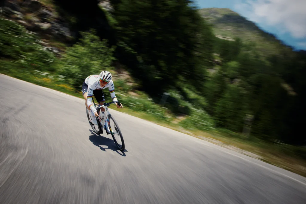 A picture showing Tour De France winner and world road champion Tadej Pogačar corning on his bicycle.